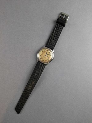 a close up of a watch on a table with a gray background