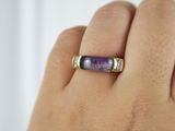 someone is holding a ring with a purple stone in it