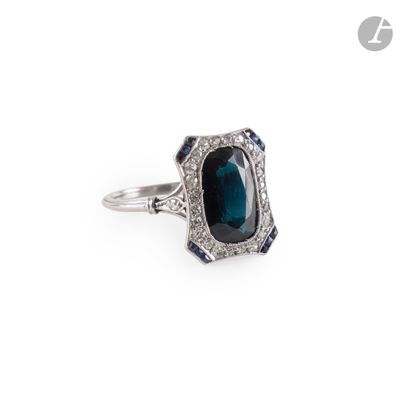 a close up of a ring on a white surface with a blue stone
