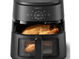 a black air fryer with a chicken inside of it