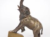 statue of an elephant balancing on a block on a white background
