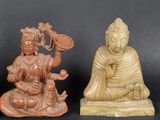two statues of buddhas are sitting on a black surface