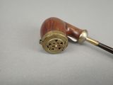 an old pipe with a wooden handle sitting on a table