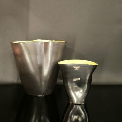 un vase en argent et un vase en argent posés sur une table noire