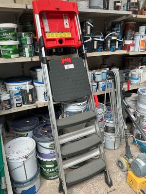 many cans of paint and a ladder in a garage