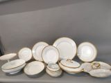 a lot of white and gold plates and bowls on a table