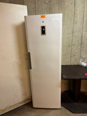 un réfrigérateur blanc posé à côté d'une table dans une pièce