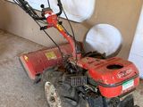 une petite débroussailleuse rouge rangée dans un garage