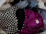 a pile of clothes that is sitting on a bed
