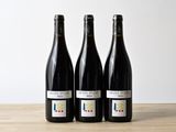 three bottles of wine sitting on top of a wooden table