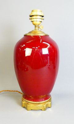 a red vase with a gold lid sitting on a table
