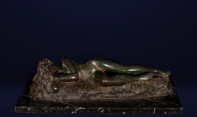 statue en bronze représentant une femme allongée sur un rocher, sur fond bleu