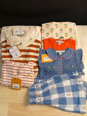 trois vêtements d'enfants sont disposés sur une surface en bois
