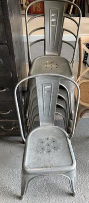 plusieurs chaises en métal et une chaise dans une pièce, à côté d'une commode