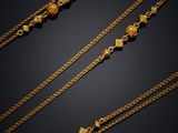 a collection of gold necklaces on a black background