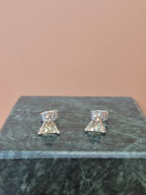 une paire de boucles d'oreilles en diamant posées sur un bloc de marbre