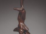 statue d'une femme tenant un oiseau, posée sur un socle en bois