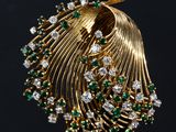 a close up of a gold broochle with green and white stones