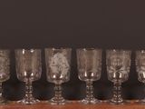 Six verres à vin sont alignés sur une table en bois