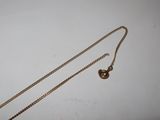 a close up of a gold necklace with a chain on a white surface