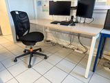 a desk with two computer monitors on it and a chair in front of it