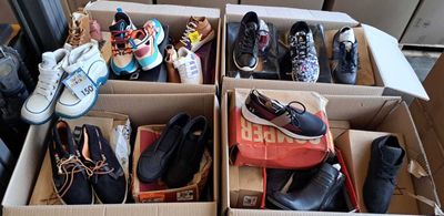 de nombreuses paires de chaussures dans des cartons posés par terre