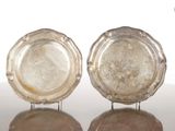 paire de plats en argent posés sur un support, sur une surface réfléchissante avec un fond blanc