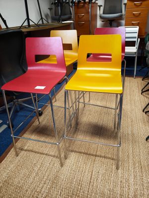 plusieurs chaises de différentes couleurs dans une pièce, avec une télévision en arrière-plan