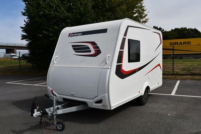 un petit camping-car blanc garé sur un parking
