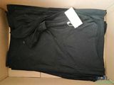 une boîte en carton ouverte contenant un t-shirt noir et une étiquette blanche