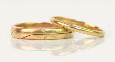 une paire d'alliances en or posées sur une surface blanche