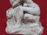 statue représentant un homme assis sur un rocher, de dos par rapport à la caméra