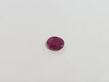 a pink oval shaped ruby stone on a white surface