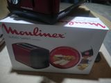 packaging of a red toaster sitting on top of a box on a table