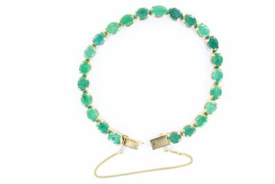 un gros plan d'un bracelet orné de pierres vertes sur fond blanc