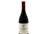 the bottle of red wine is sitting on a white surface