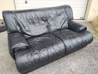 a black leather couch sitting in front of a garage door