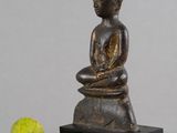 statue représentant une personne assise sur un rocher à côté d'une balle de tennis