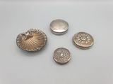 trois boutons en argent et un coquillage en argent sur un fond blanc