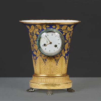 un vase doré et bleu sur lequel est représentée une horloge