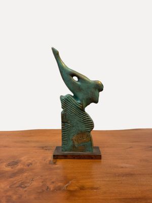 sculpture en bronze représentant un oiseau posée sur une table en bois