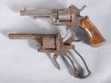 two old revolvers that are on a white surface