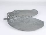 a silver plate with a flower on it on a white surface