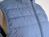 the back of a woman ' s blue vest with a zipper down the front