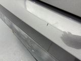 the front bumper of a silver car with a black spot on it