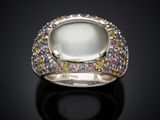 a close up of a ring with a white stone surrounded by multi colored stones