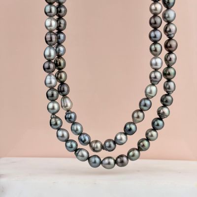 un gros plan d'un collier de perles noires sur fond rose