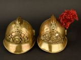 pair of brass helmets with a red feather on top of them