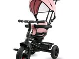 Le tricycle est rose et noir, avec un auvent rose.