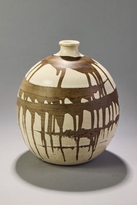 a white and brown vase sitting on a table
